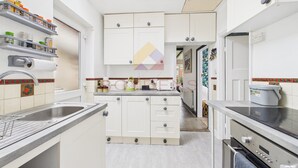 Een compacte keuken met witte kastjes, een roestvrijstalen spoelbak en een inbouwoven.
