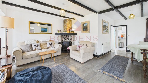 Een gezellige woonkamer met een bank, fauteuils, een salontafel en een open haard.