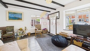 Een woonkamer met een groot raam, een televisie, een houten stoel, een bank en een vloerkleed.