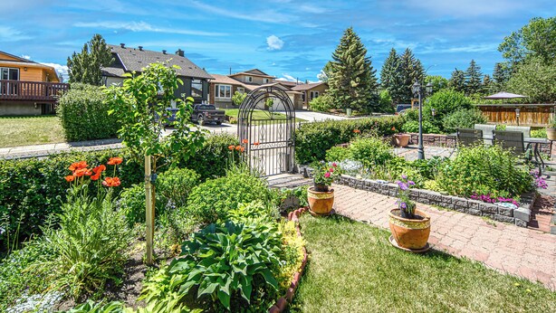 A residential neighborhood with well-maintained gardens, a metal gate, and houses with various roof styles. - Spacious Home Near Stampede & Downtown Fully Fenced Yard Double Garage Pet OK (Calgary)