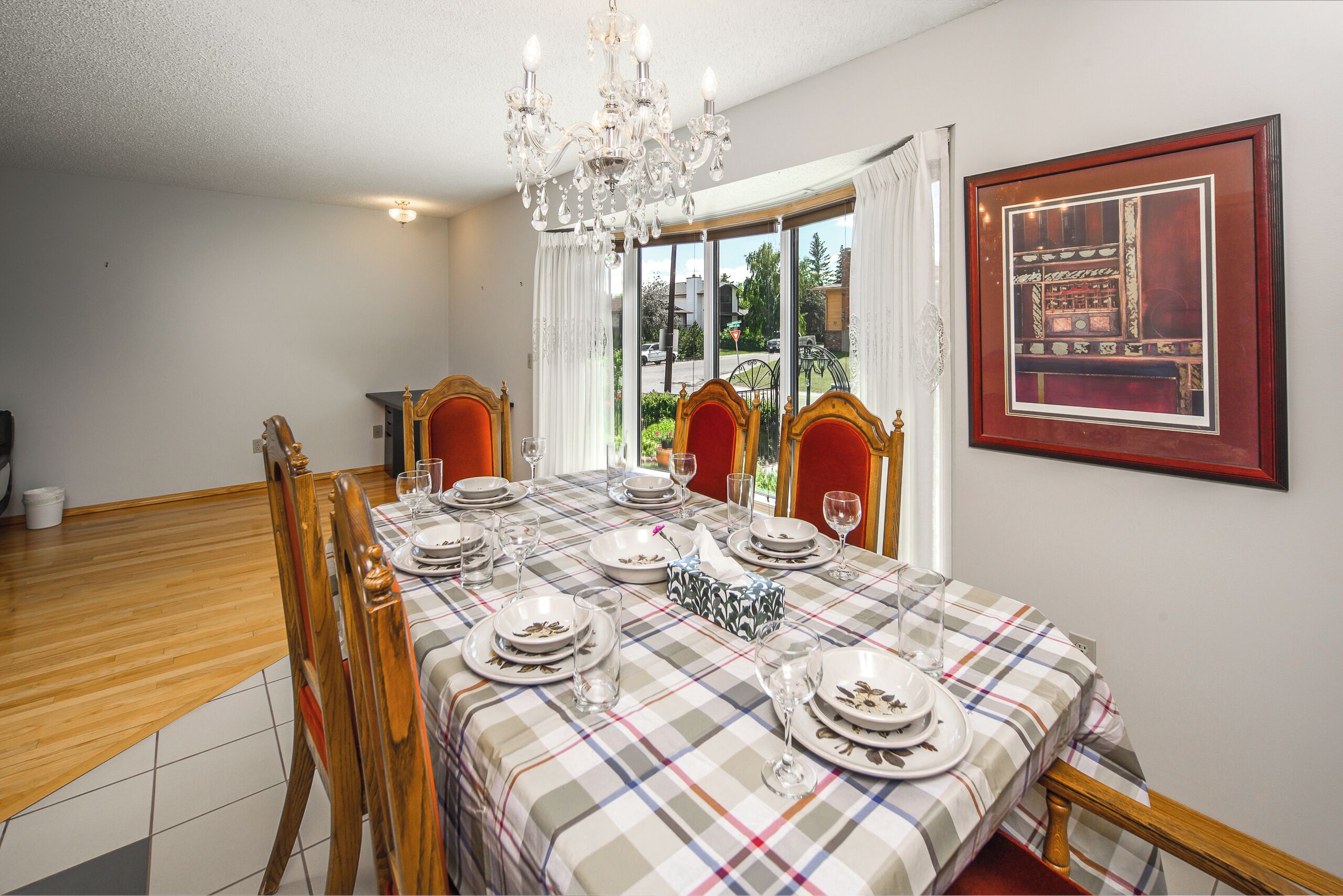 A dining room with a checkered tablecloth, wooden chairs, and a chandelier.