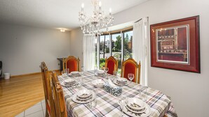 A dining room with a checkered tablecloth, wooden chairs, and a chandelier. - Spacious Home Near Stampede & Downtown Fully Fenced Yard Double Garage Pet OK (Calgary)