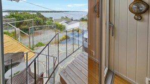 Un balcon donnant sur un plan d’eau, une terrasse en bois et des meubles en osier.