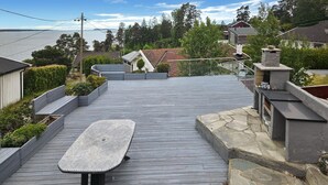 Une terrasse en bois avec une table en métal, entourée de murs en pierre et de verdure.