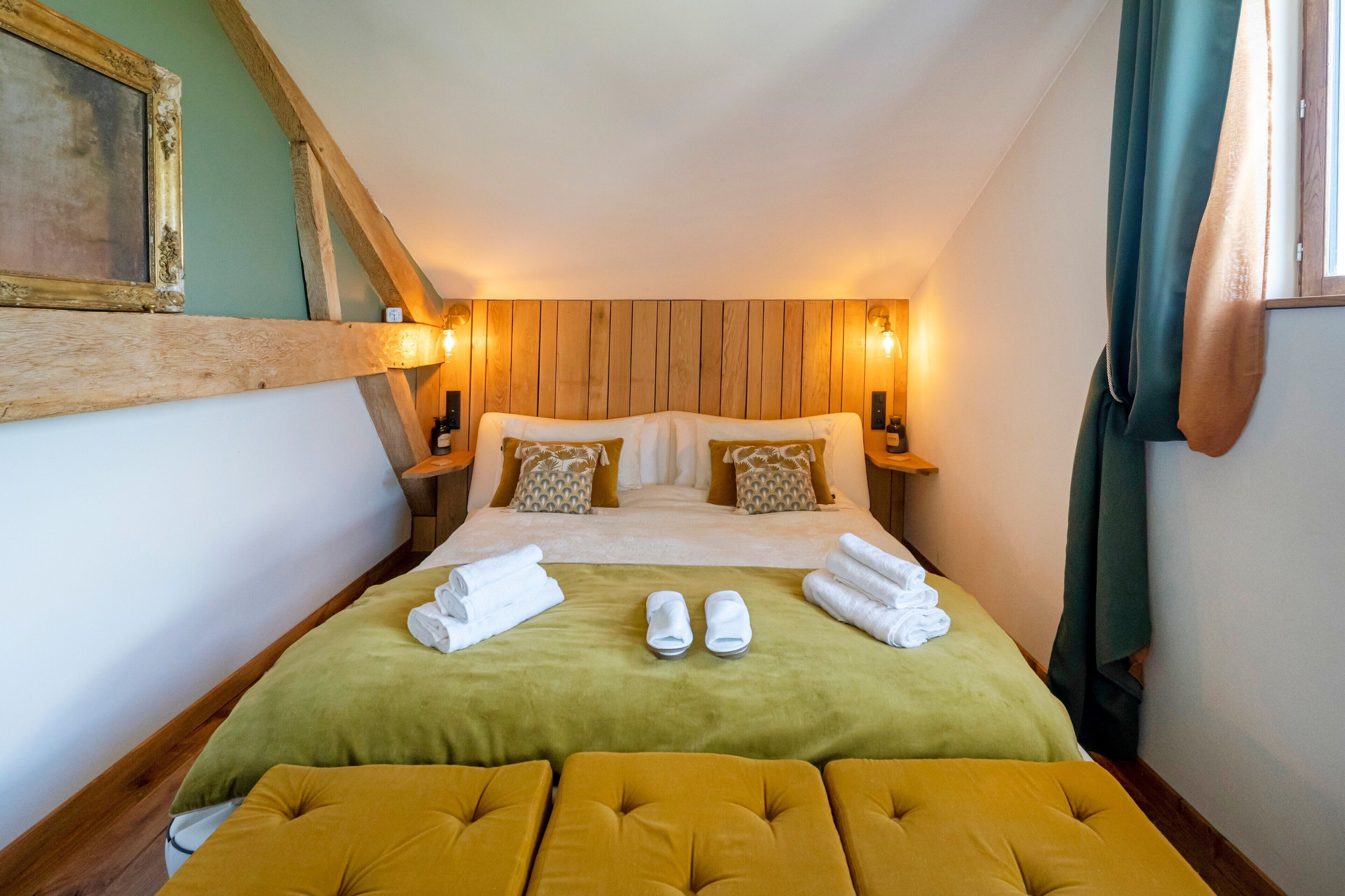 Hotelkamer met houten hoofdbord, een bed met groen-witte beddengoed, twee nachtkastjes met lampen, en een groen gordijn.