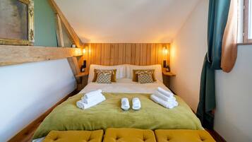 Hotelkamer met houten hoofdbord, een bed met groen-witte beddengoed, twee nachtkastjes met lampen, en een groen gordijn.