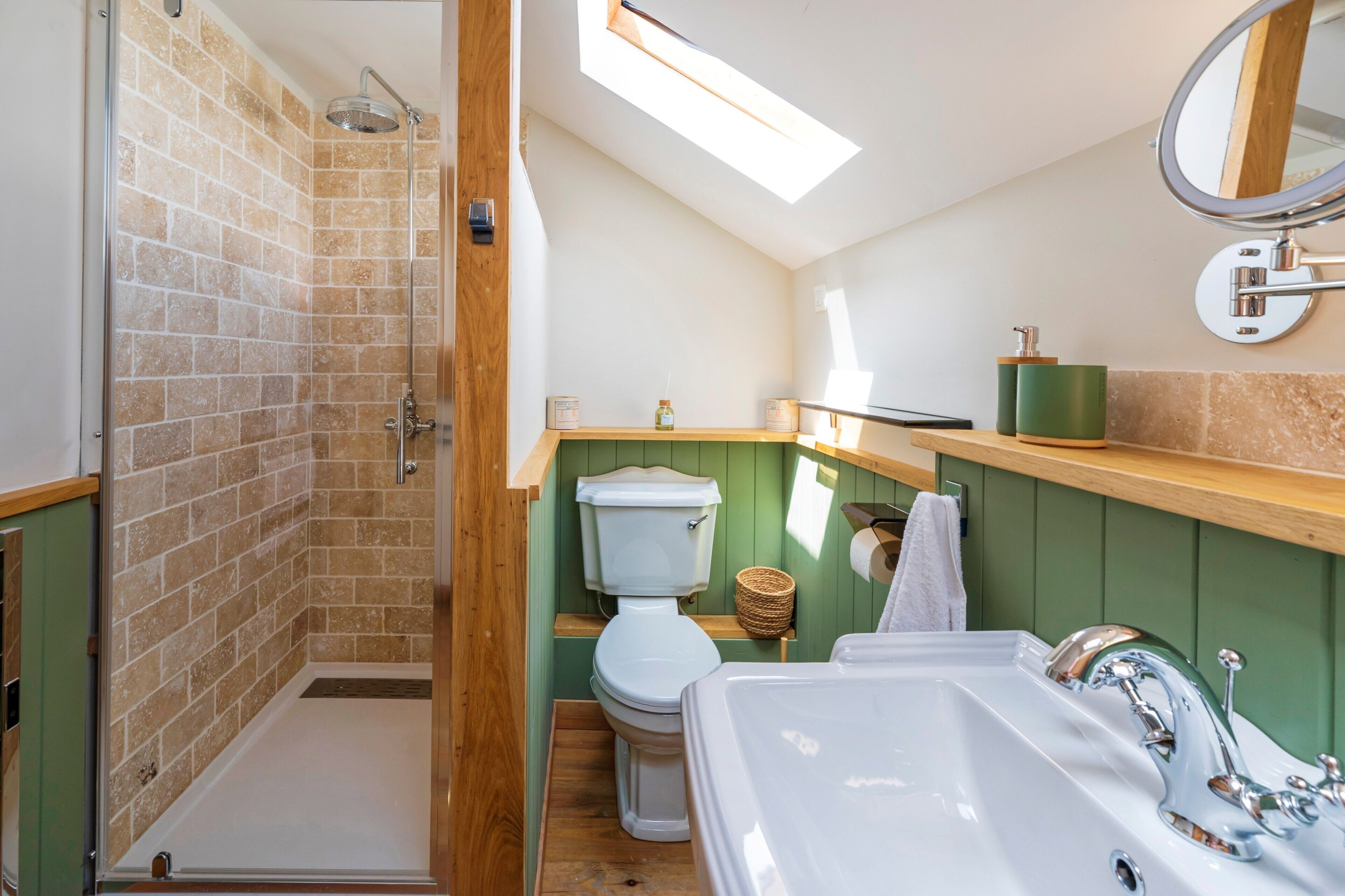 Une salle de bain équipée d’une douche, de toilettes, d’un lavabo et d’une lucarne.