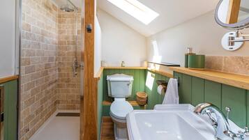 Une salle de bain équipée d’une douche, de toilettes, d’un lavabo et d’une lucarne.