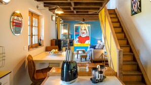 A dining area with a table, chairs, a coffee machine, and a wall with a poster. - L'Atelier de Scarlett – An Intimate Luxury Escape in the Heart of Gascony (Unknown)