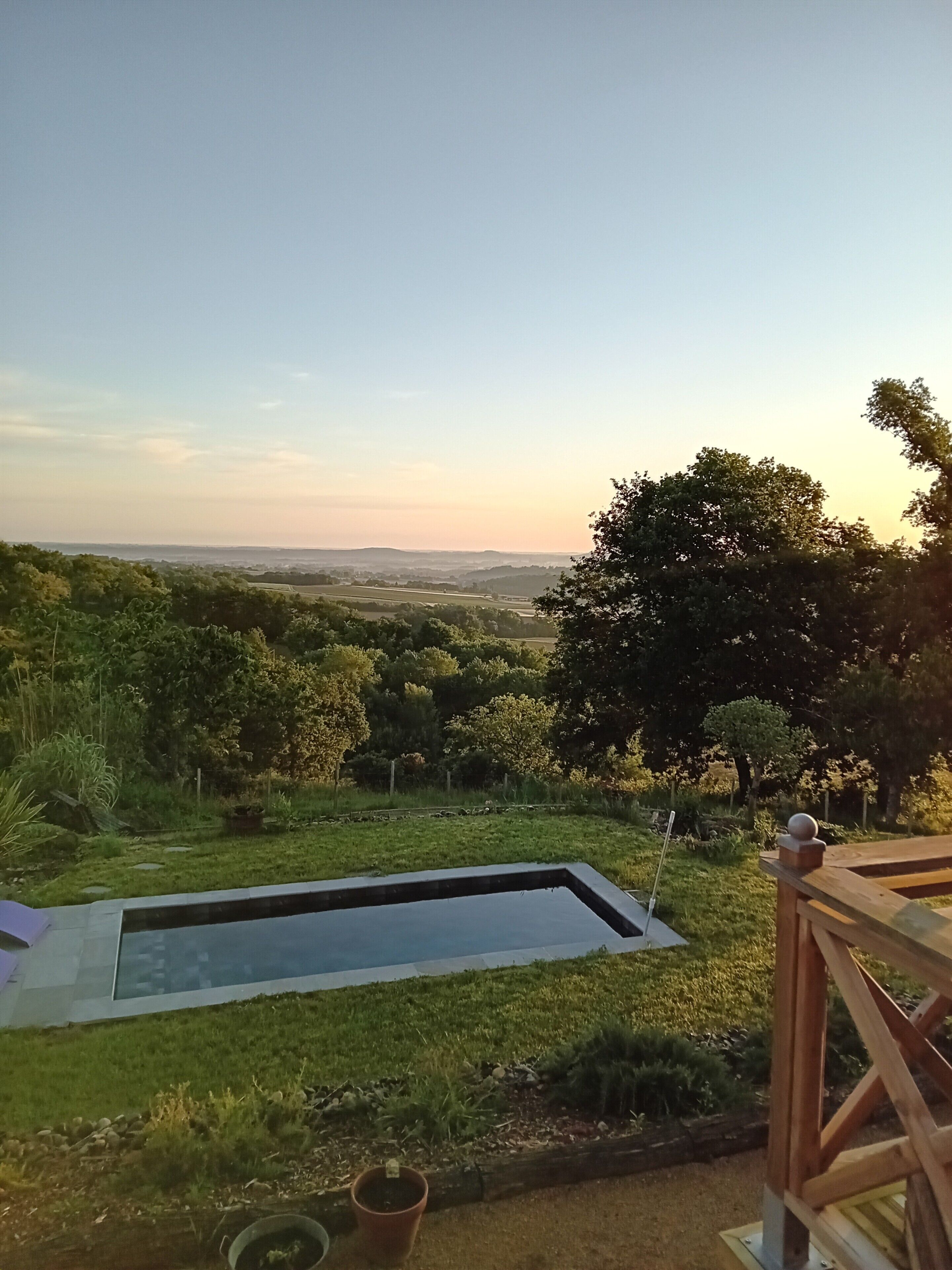 A pool with a view of a green landscape and distant hills.