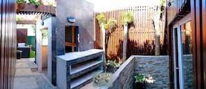 Une terrasse extérieure moderne dotée d’un espace salon intégré, d’une clôture en bois et d’un mur en pierre.