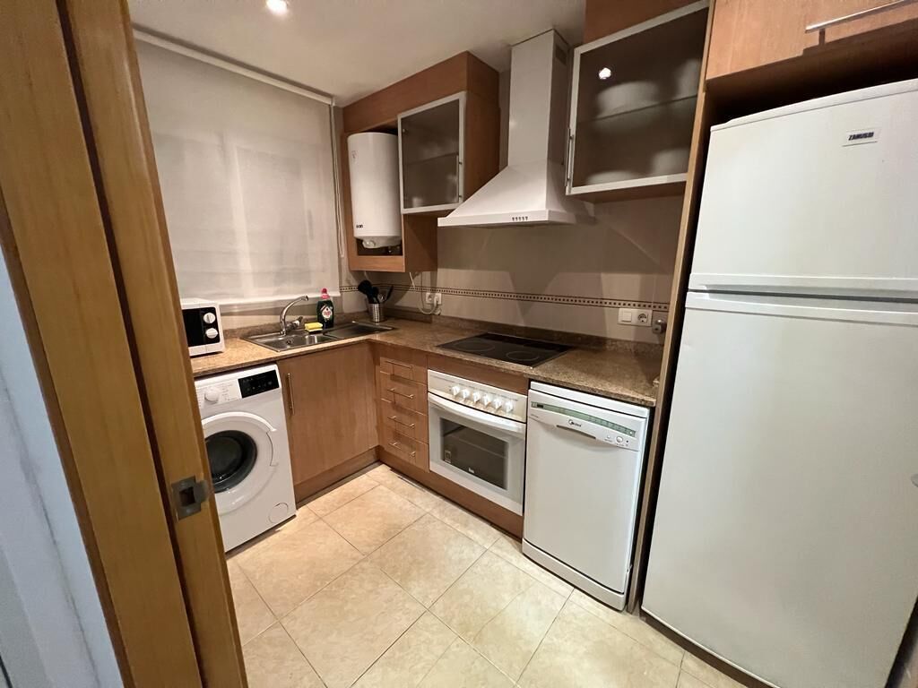 Cuina compacta amb rentadora, forn, rentavaixelles i nevera.