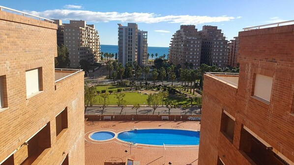 A view of a residential building with a swimming pool and a landscaped garden.