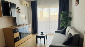 A living room with a sofa, TV, cabinet, and a plant.