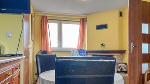 A dining area with a table, chairs, a television, and a dog.