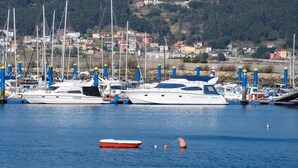 A marina with several yachts docked, a small red boat, and a backdrop of a coastal town with houses. - Apartment in Cabo Cruz with Sea Views (Unknown)