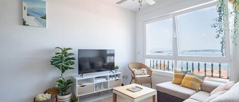 A modern living room with a television, sofa, and a large window offering a view.