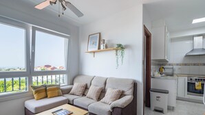 A living room with a sofa, a small table, and a view through large windows. - Apartment in Cabo Cruz with Sea Views (Unknown)