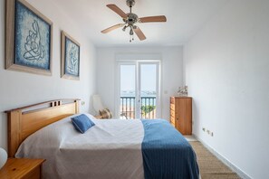 A bedroom with a bed, a ceiling fan, a dresser, and a view of the outdoors. - Apartment in Cabo Cruz with Sea Views (Unknown)