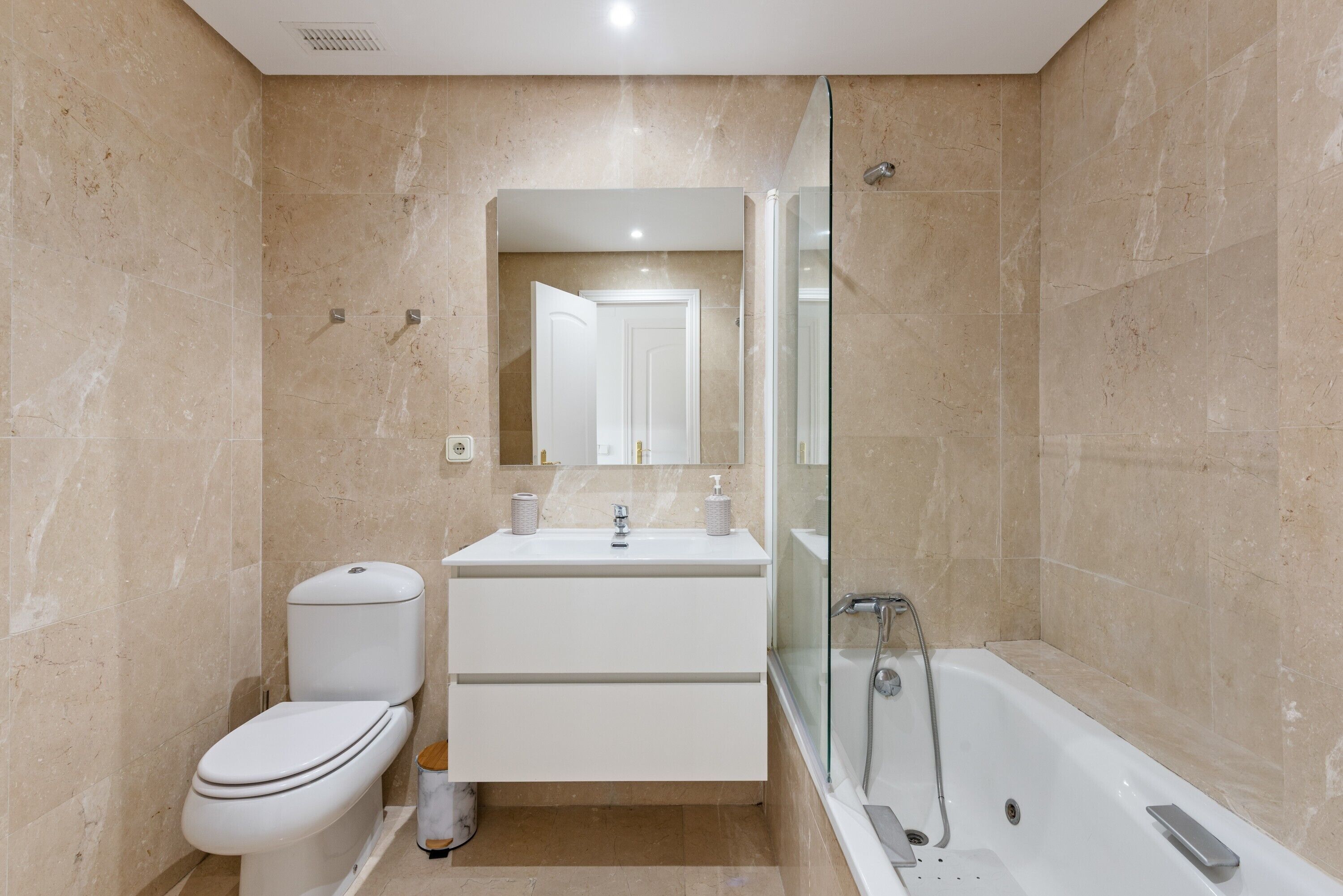 Een moderne badkamer met toilet, wastafel en douchecabine met glazen wanden.