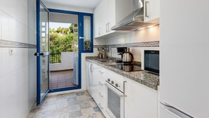 A kitchen with white cabinets, a stainless steel range hood, a microwave, and a coffee maker.