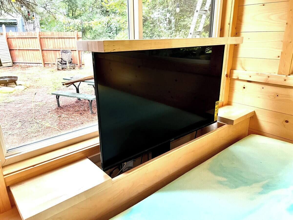Un mueble bajo de madera con un televisor de pantalla plana en una habitación con ventana.