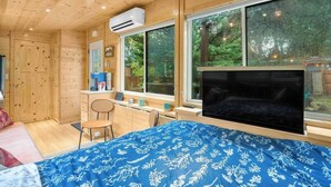 Una habitación de cabaña de madera con cama, escritorio, silla y ventanas amplias.