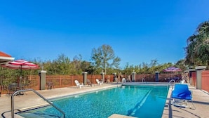 A rectangular swimming pool with a metal ladder, surrounded by a wooden deck and lounge chairs. - Stay Express Inn & Suites - Mobile AL (Mobile)