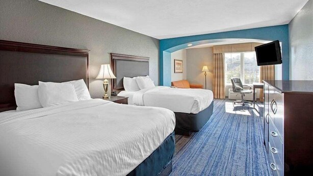 A hotel room with two beds, a desk, a chair, a TV, and a view of the outdoors. - Stay Express Inn & Suites - Mobile AL (Mobile)