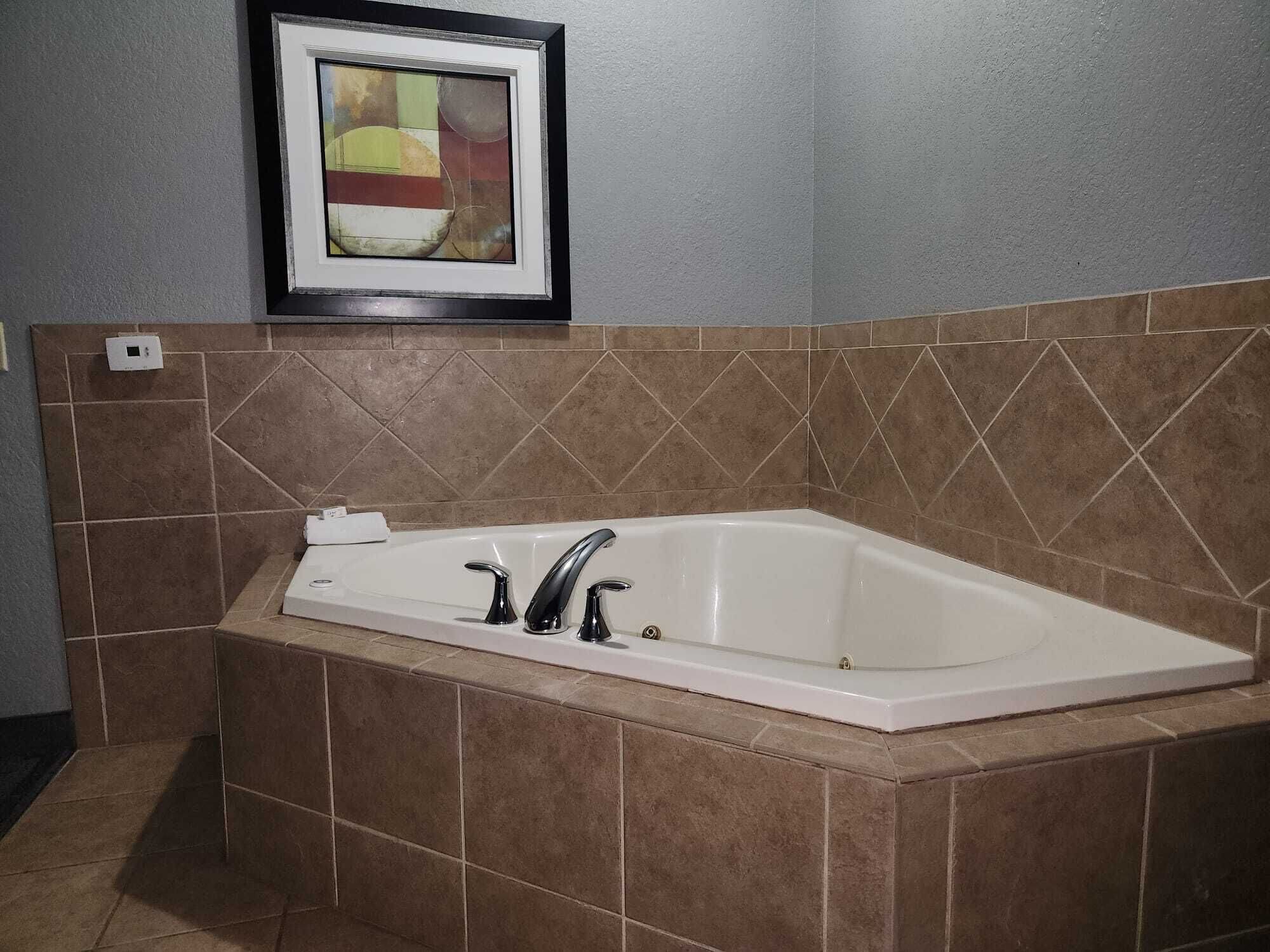 A bathroom with a freestanding bathtub, tiled walls, and a framed abstract painting above the tub.