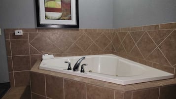 Un baño con una bañera independiente, paredes con azulejos y un cuadro abstracto enmarcado sobre la bañera.