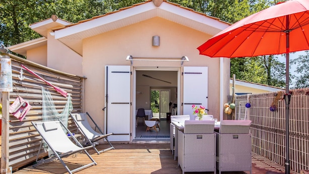 A wooden deck with lounge chairs, a red umbrella, and a building entrance. - Maison Escapades Marines – Terrace and Comfort in the Heart of the Village (Arès)