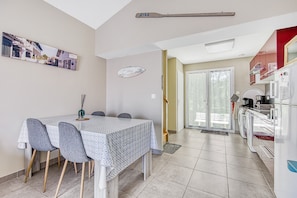 Un comedor con mesa y sillas, una cocina equipada y un ventanal corredero que da a un espacio exterior.