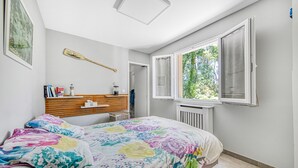 A bedroom with a bed, a window, a radiator, and a wooden headboard. - Maison Escapades Marines – Terrace and Comfort in the Heart of the Village (Arès)
