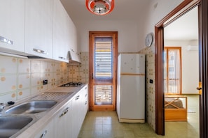 Una cocina con gabinetes blancos, un lavamanos, una estufa y un refrigerador.