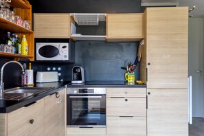 Een moderne keuken met houten kastjes, een magnetron, een broodrooster, een koffiezetapparaat en een inbouwoven.