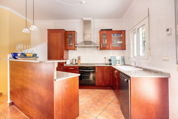 A kitchen with wooden cabinets, a stove, and a sink.