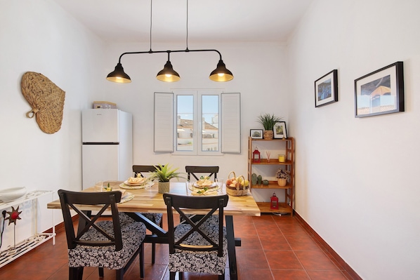 Un espace repas comprenant une table en bois, des chaises et un luminaire suspendu au plafond.