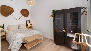 A bedroom with a bed, bedside tables, a bench, a wardrobe, and a hanging light fixture.