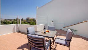 A terrace with a table, chairs, and a bottle of wine.