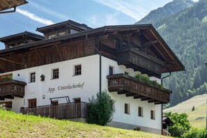 Un bâtiment traditionnel en bois, doté de balcons et d’une enseigne indiquant « App. Unteracherhof ».