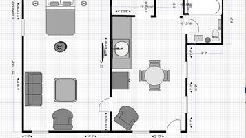A floor plan of a hotel room with a bed, a desk, a chair, a sofa, a small table, and a bathroom.
