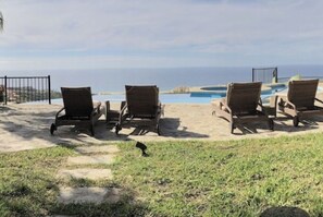 Ein Poolbereich mit Liegestühlen und Blick auf den Ozean.