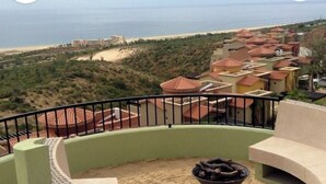 Un balcón con vistas a una playa y edificios de un complejo turístico.