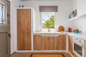 Una cocina con armarios de madera, una ventana que da a zonas verdes, un fregadero y una encimera con utensilios de cocina.