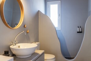 A bathroom with a white sink, a mirror, a toilet, and a shower.