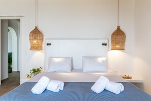 A hotel room with a large bed, two bedside tables, a wall-mounted light fixture, and a potted plant.