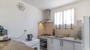 Cocina compacta con lavadora, estufa y lavamanos.