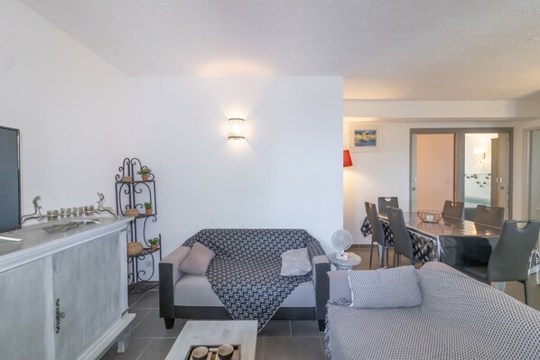 Una sala de estar con sofá, una mesa de comedor y una zona de cocina.
