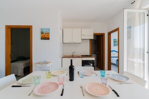 A dining table set with plates, glasses, and cutlery, a bottle, and a small side table with a book.